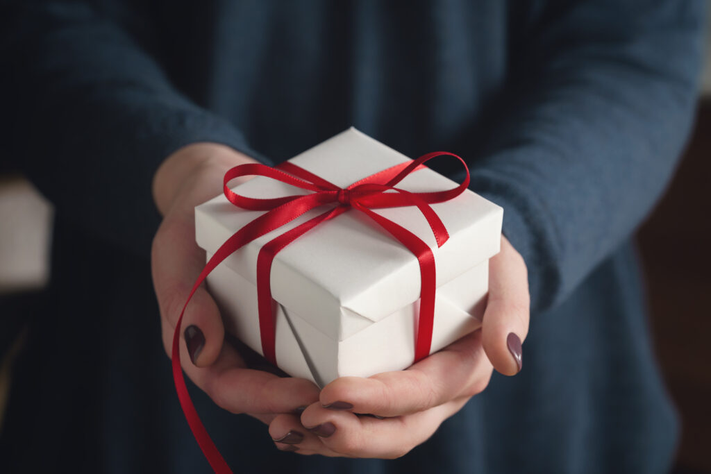 young female hands holding gift box with red ribbon, shallow focus
